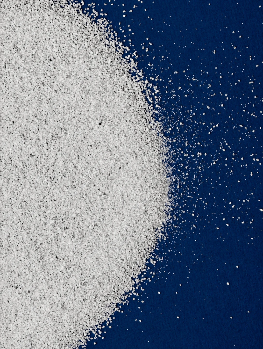White industrial granules arranged across a deep blue surface