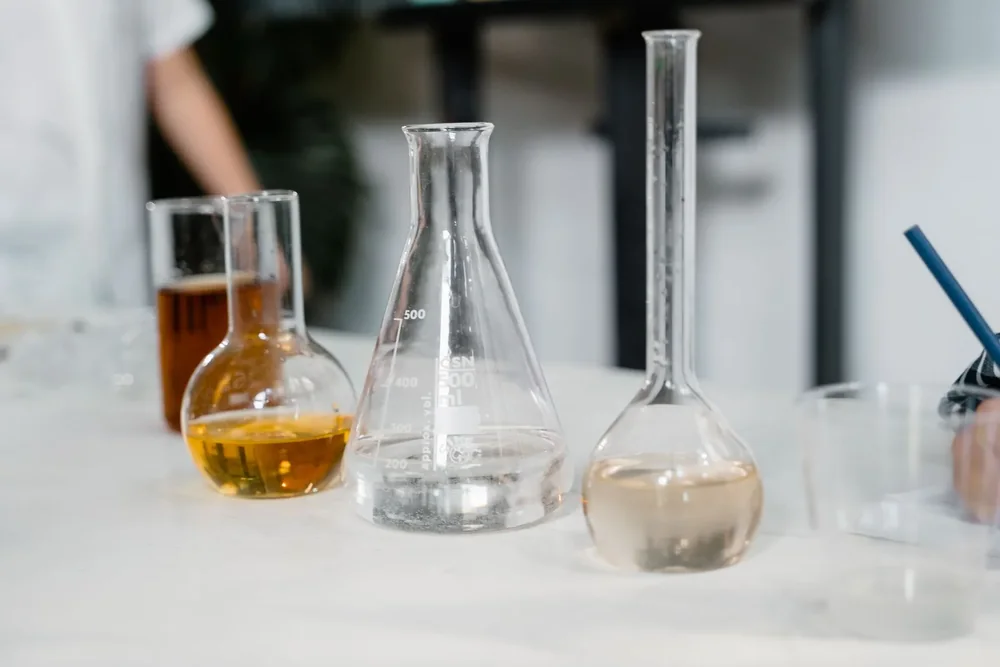 Laboratory beakers and flasks with liquid samples on a bench