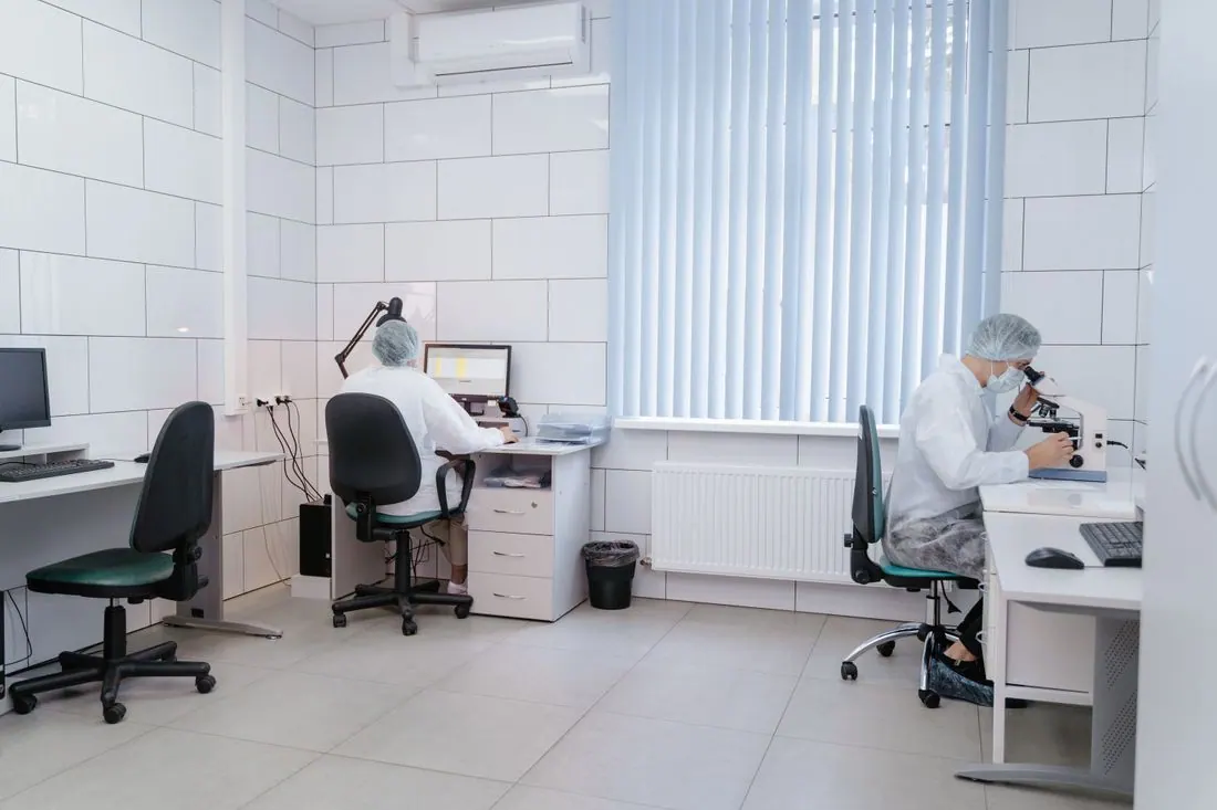 Laboratory technicians using computers and microscopes